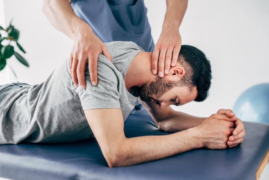 How Can Chiropractic Care Help Shoulder Injuries? Chiropractor massaging shoulder and neck of man on Massage Table in hospital
Shoulder injuries